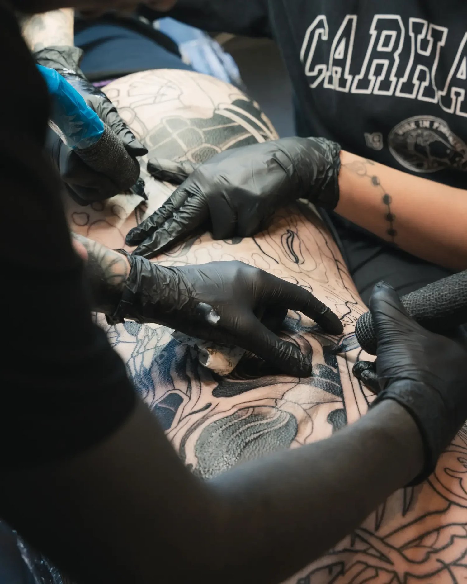 Two tattoo artists collaborating on a tattoo at Cobra Gold Tattoo Studio